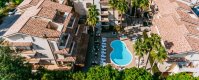 Piscina a forma di fagiolo tra palme e edifici.
